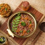 Traditional Ayurvedic Karkidaka Kanji served in a brass vessel with herbal side dishes on a woven mat.