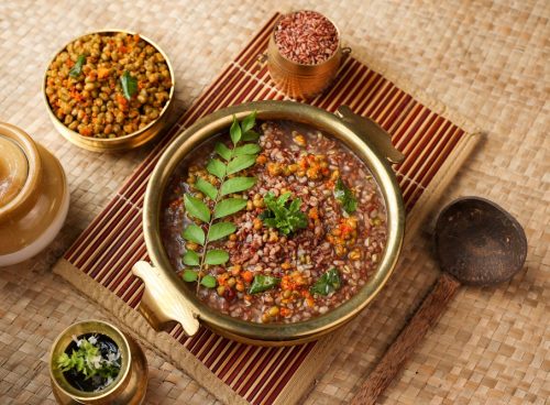 Traditional Ayurvedic Karkidaka Kanji served in a brass vessel with herbal side dishes on a woven mat.
