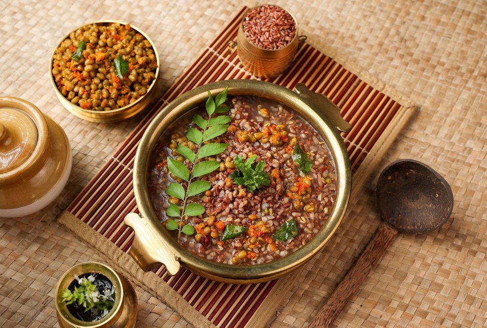 Traditional Ayurvedic Karkidaka Kanji served in a brass vessel with herbal side dishes on a woven mat.