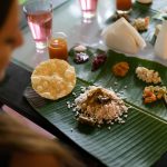 Traditional Ayurvedic meal served on banana leaf with rice, curry, vegetables, and herbal beverages arranged according to ancient nutritional principles.