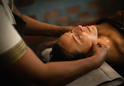 Woman receiving traditional Ayurvedic facial massage with herbal oil at Kairali Ayurvedic Healing Village in Kerala