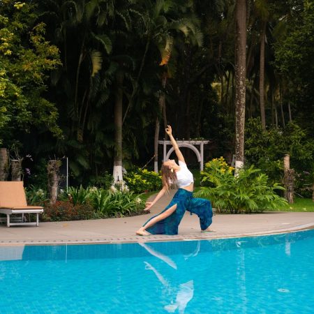 Woman practicing yoga near a serene pool surrounded by lush greenery at Kairali Ayurvedic Health Retreat in Kerala