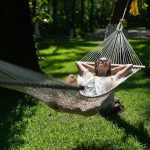 Woman relaxing on a hammock under the shade of trees at Kairali – The Ayurvedic Healing Village in Kerala.