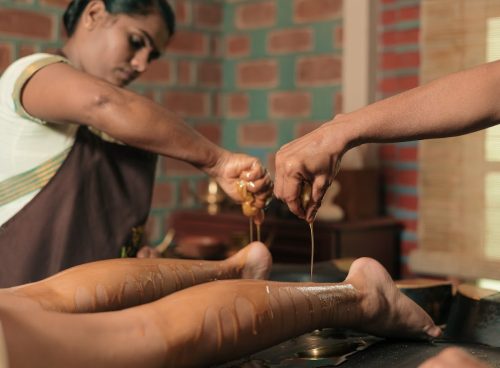 Traditional Ayurvedic oil therapy at Kairali Ayurvedic Health Village in Kerala, where therapists apply warm herbal oils for holistic healing and rejuvenation.
