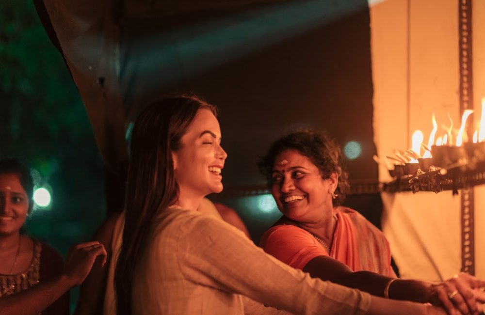 Women lighting traditional oil lamps during a cultural ceremony at Kairali – The Ayurvedic Healing Village in Kerala.