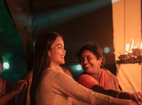 Women lighting traditional oil lamps during a cultural ceremony at Kairali – The Ayurvedic Healing Village in Kerala.