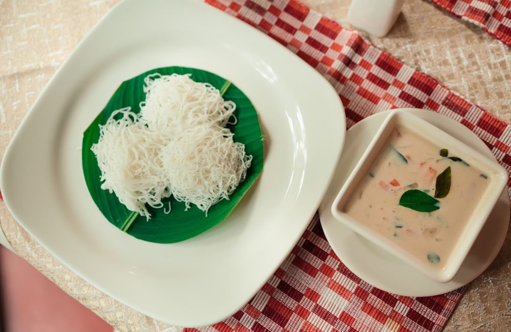 Traditional Kerala-style idiyappam with coconut vegetable stew served on a banana leaf at an Ayurvedic retreat.