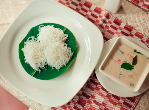 Traditional Kerala-style idiyappam with coconut vegetable stew served on a banana leaf at an Ayurvedic retreat.