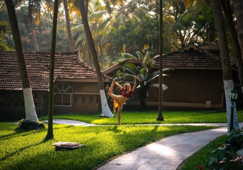 Woman practicing yoga outdoors at Kairali Ayurvedic Health Village, Kerala.