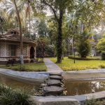 Traditional Kerala-style villa surrounded by palm trees at Kairali Ayurvedic Healing Village, Palakkad