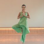 Woman practicing tree pose (Vrikshasana) on yoga mat at Ayurvedic wellness center in Kerala