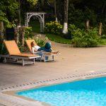 Woman relaxing by the poolside at Kairali Ayurvedic Healing Village surrounded by lush greenery in Kerala