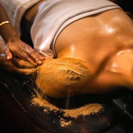 Ayurvedic herbal powder massage (Udwarthanam) being performed on a woman at Kairali Ayurvedic Health Village in Kerala.