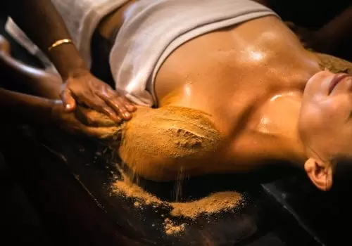 Ayurvedic herbal powder massage (Udwarthanam) being performed on a woman at Kairali Ayurvedic Health Village in Kerala.
