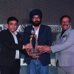 Three men holding an award trophy at the Global Tourism Awards 2025, representing Kairali Ayurvedic Healing Village's win as Best Wellness Resort.