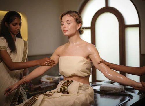 Kairali Ayurvedic therapists performing synchronized Abhyanga oil massage on a guest at the Healing Village in Kerala