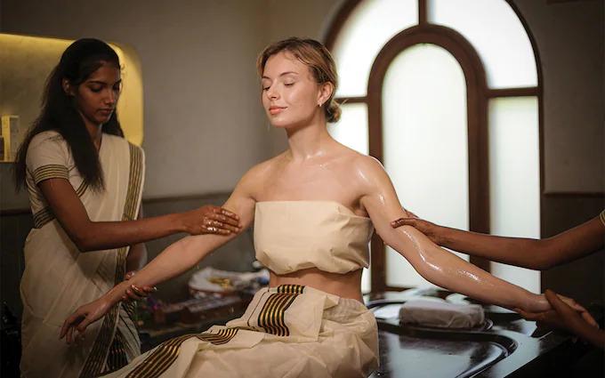 Kairali Ayurvedic therapists performing synchronized Abhyanga oil massage on a guest at the Healing Village in Kerala