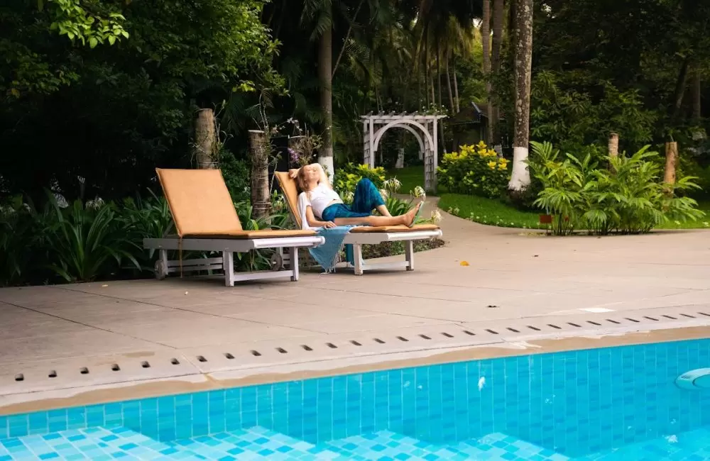 Solo female traveller relaxing by the pool at a lush Ayurvedic retreat in Kerala, India—calm, women-led, safety-first setting.