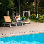 Solo female traveller relaxing by the pool at a lush Ayurvedic retreat in Kerala, India—calm, women-led, safety-first setting.
