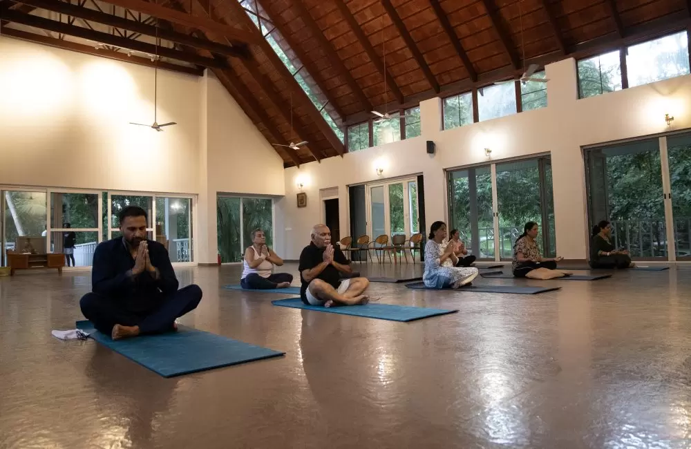 Group meditation in airy yoga hall at Kairali Ayurvedic Healing Village, Kerala.