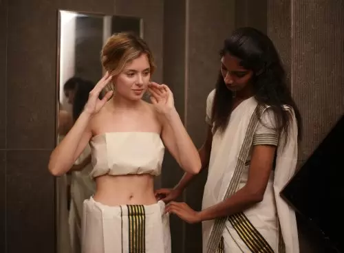 Ayurvedic therapist in a traditional Kerala saree assisting a solo woman guest to drape treatment attire before therapy at Kairali in Palakkad, Kerala.