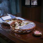 Ayurvedic therapy setup with warm herbal oils, linen potli compresses, incense smoke and candle at Kairali – The Ayurvedic Healing Village