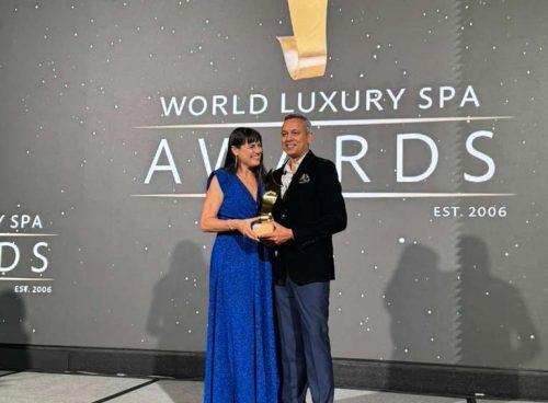 Award ceremony photo: Kairali representative receiving a World Luxury Spa Awards trophy on stage, against the event backdrop.