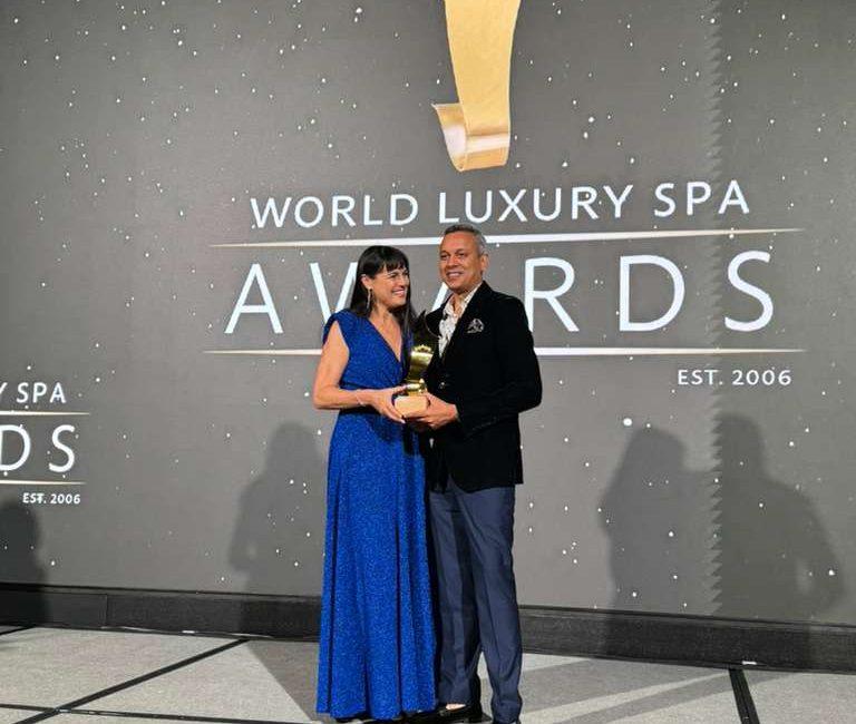 Award ceremony photo: Kairali representative receiving a World Luxury Spa Awards trophy on stage, against the event backdrop.