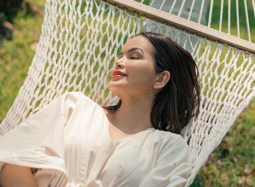 Relaxed solo female traveler resting on a hammock in lush greenery at a Kerala wellness retreat.