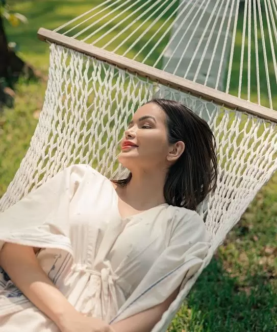 Relaxed solo female traveler resting on a hammock in lush greenery at a Kerala wellness retreat.