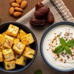 Spiced paneer cubes with saffron and herbs beside a bowl of cumin-mint yogurt