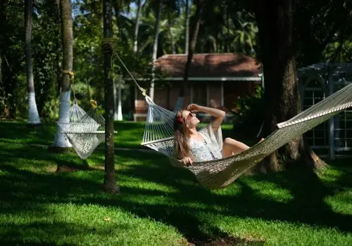 Solo traveler relaxing on a hammock amid coconut palms at Kairali – The Ayurvedic Healing Village, Palakkad, Kerala.