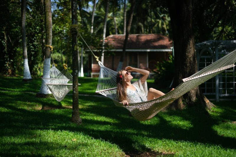 Solo traveler relaxing on a hammock amid coconut palms at Kairali – The Ayurvedic Healing Village, Palakkad, Kerala.