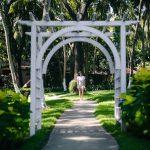 Solo woman walking along a curved garden path under a white arch at Kairali – The Ayurvedic Healing Village, Palakkad.