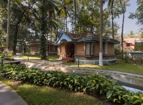 Traditional Kerala cottage surrounded by palm trees at Kairali Ayurvedic Health Retreat Kerala, designed for peaceful solo female Ayurveda stays