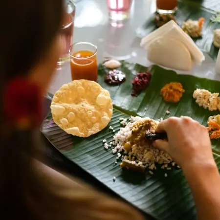 Guest enjoying a Kerala banana-leaf meal—rice, dal, papad and seasonal veg sides—at Kairali Ayurvedic Healing Village.