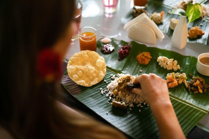 Guest enjoying a Kerala banana-leaf meal—rice, dal, papad and seasonal veg sides—at Kairali Ayurvedic Healing Village.