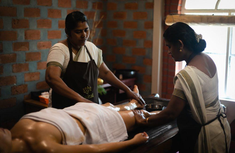 Ayurvedic therapists performing a traditional Abhyanga oil massage as part of a physician-guided Panchakarma program in Kerala.