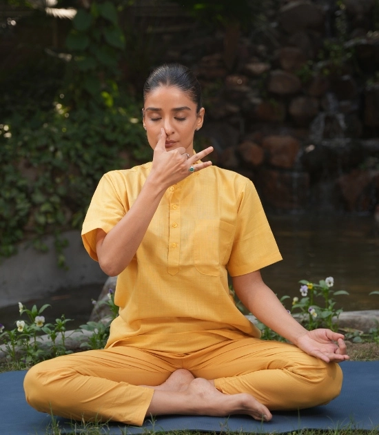 Woman practicing seated pranayama breathing exercise outdoors, an easy office-friendly yoga practice for people who sit all day