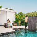 Couple relaxing by the infinity pool at Villa Raag in South Goa, surrounded by tropical greenery and a waterfall feature.