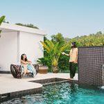 Couple relaxing by the infinity pool at Villa Raag in South Goa, surrounded by tropical greenery and a waterfall feature.