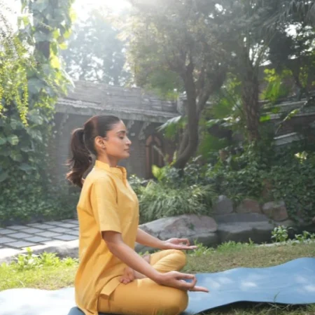 Woman practising meditation outdoors, illustrating yoga and Ayurveda for stress support.