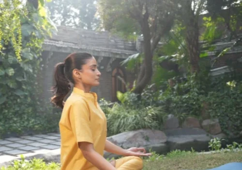 Woman practising meditation outdoors, illustrating yoga and Ayurveda for stress support.