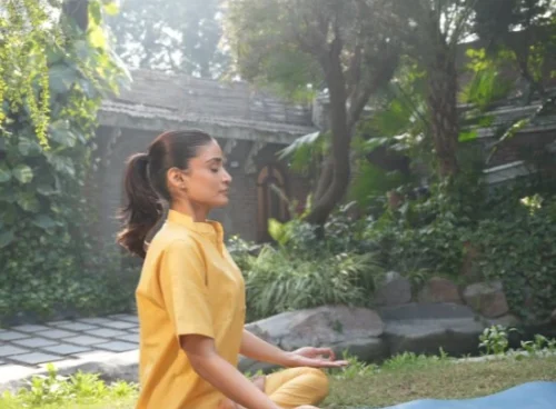Woman practising meditation outdoors, illustrating yoga and Ayurveda for stress support.