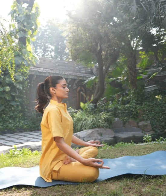 Woman practising meditation outdoors, illustrating yoga and Ayurveda for stress support.