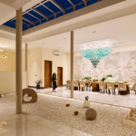 Open-to-sky dining pavilion at Villa Raag with a long table, teal chandelier, sculptural wall art, and a zen gravel court.
