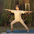Woman practising Warrior II (Virabhadrasana II) during a Yoga and meditation retreat in Kerala at Kairali – The Ayurvedic Healing Village.