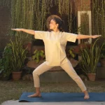 Woman practising Warrior II (Virabhadrasana II) during a Yoga and meditation retreat in Kerala at Kairali – The Ayurvedic Healing Village.