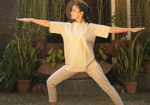 Woman practising Warrior II (Virabhadrasana II) during a Yoga and meditation retreat in Kerala at Kairali – The Ayurvedic Healing Village.