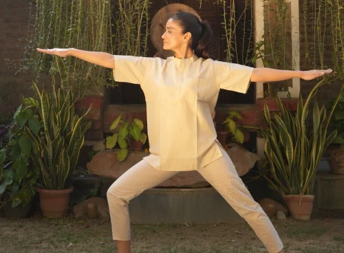 Woman practising Warrior II (Virabhadrasana II) during a Yoga and meditation retreat in Kerala at Kairali – The Ayurvedic Healing Village.